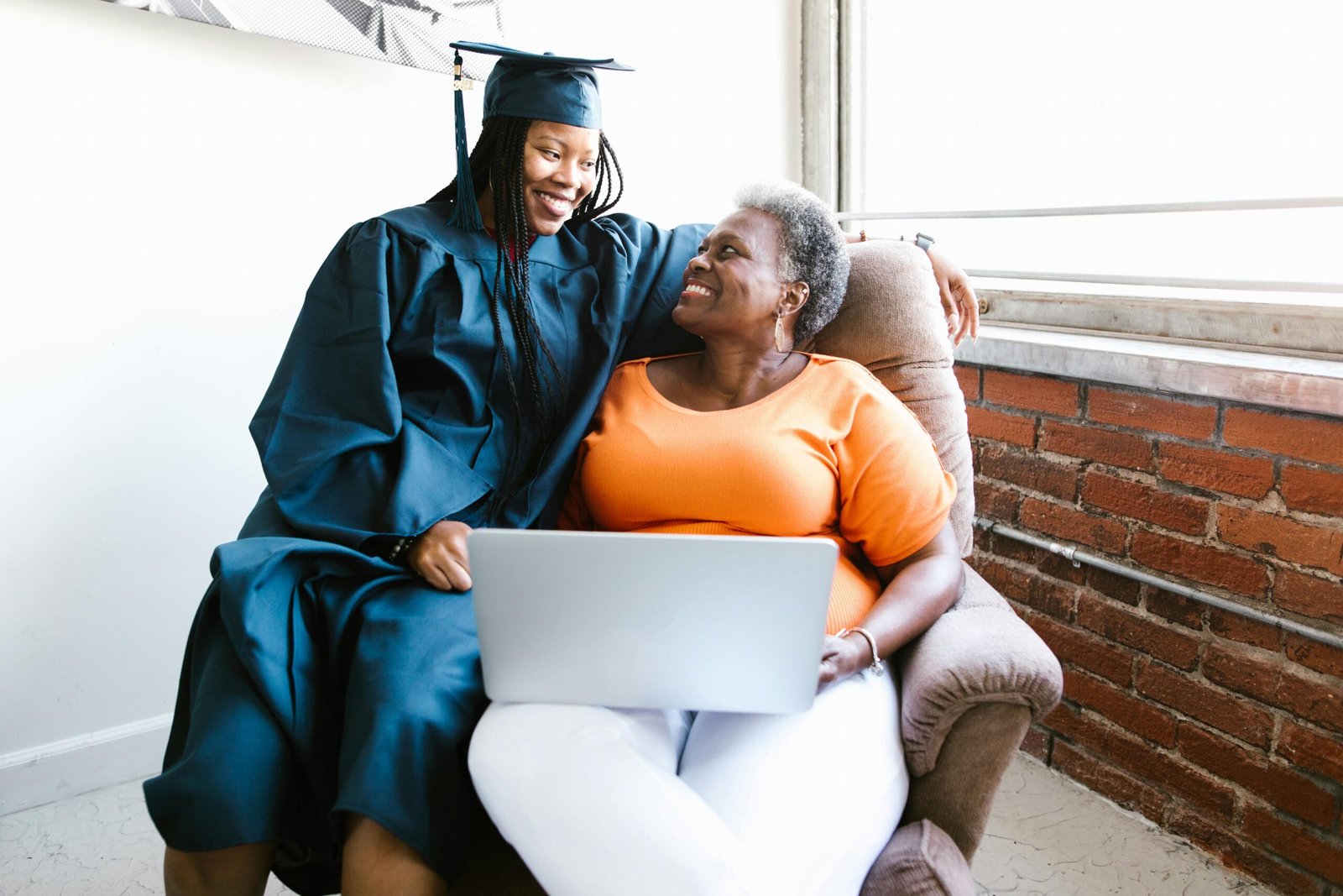 A proud graduate sharing a joyful moment with her mother at home, showcasing happiness and achievement.